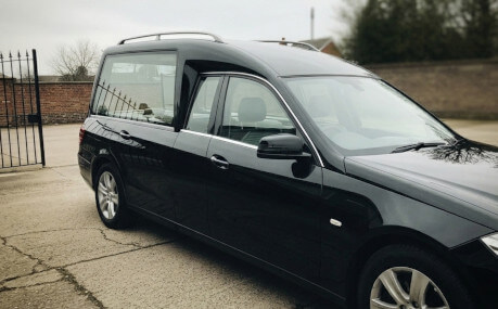 Moderno carro funebre nero parcheggiato all'esterno di un'abitazione.